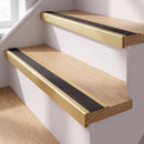 Gold anodised self-adhesive 46x30mm stair nosing with black anti-slip rubber insert fitted to oak timber stairs in a home