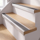 Silver anodised self-adhesive 46x30mm stair nosing with grey anti-slip rubber insert fitted to oak timber stairs in a home