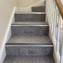 Silver anodised aluminium stair nosing with twin black rubber inserts fitted across the full width of carpeted stairs in a UK home