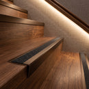 Dark bronze aluminium stair nosing with coal insert on walnut treads in a hotel corridor staircase