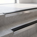 Square-edge aluminium stair nosing with a deep 56mm riser face fixed directly to bare concrete steps with no floor covering, showing the flat tread plate, ramped rear edge and the full depth of the square front face down the riser