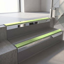 Square-edge aluminium stair nosing with a deep 56mm riser face in Bright Polished, fitted along two vinyl-covered concrete steps in an office stairwell, with an Apple Green anti-slip PVC insert running the full width of each step