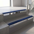 Square-edge aluminium stair nosing with a deep 56mm riser face in Bright Polished, fitted along two vinyl-covered concrete steps in an office stairwell, with a Dark Blue anti-slip PVC insert running the full width of each step