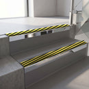 Square-edge aluminium stair nosing with a deep 56mm riser face in Bright Polished, fitted along two vinyl-covered concrete steps in an office stairwell, with a Hazard anti-slip PVC insert running the full width of each step