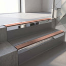 Square-edge aluminium stair nosing with a deep 56mm riser face in Bright Polished, fitted along two vinyl-covered concrete steps in an office stairwell, with a Mid Brown anti-slip PVC insert running the full width of each step
