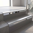 Square-edge aluminium stair nosing with a deep 56mm riser face in Bright Polished, fitted along two vinyl-covered concrete steps in an office stairwell, with a Polar Grey anti-slip PVC insert running the full width of each step