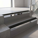 Square-edge aluminium stair nosing with a deep 56mm riser face in Bright Polished, fitted along two vinyl-covered concrete steps in an office stairwell, with a Premium Black anti-slip PVC insert running the full width of each step
