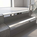 Square-edge aluminium stair nosing with a deep 56mm riser face in Bright Polished, fitted along two vinyl-covered concrete steps in an office stairwell, with a White anti-slip PVC insert running the full width of each step