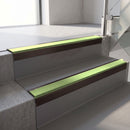 Square-edge aluminium stair nosing with a deep 56mm riser face in Dark Bronze, fitted along two vinyl-covered concrete steps in an office stairwell, with an Apple Green anti-slip PVC insert running the full width of each step