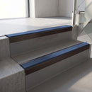 Square-edge aluminium stair nosing with a deep 56mm riser face in Dark Bronze, fitted along two vinyl-covered concrete steps in an office stairwell, with a Blue anti-slip PVC insert running the full width of each step