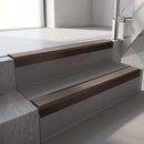 Square-edge aluminium stair nosing with a deep 56mm riser face in Dark Bronze, fitted along two vinyl-covered concrete steps in an office stairwell, with a Brown anti-slip PVC insert running the full width of each step