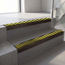 Square-edge aluminium stair nosing with a deep 56mm riser face in Dark Bronze, fitted along two vinyl-covered concrete steps in an office stairwell, with a Hazard anti-slip PVC insert running the full width of each step