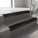 Square-edge aluminium stair nosing with a deep 56mm riser face in Dark Bronze, fitted along two vinyl-covered concrete steps in an office stairwell, with a Premium Black anti-slip PVC insert running the full width of each step