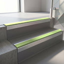Square-edge aluminium stair nosing with a deep 56mm riser face in Mill Finish, fitted along two vinyl-covered concrete steps in an office stairwell, with an Apple Green anti-slip PVC insert running the full width of each step