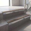 Square-edge aluminium stair nosing with a deep 56mm riser face in Mirroflect Silver, fitted along two vinyl-covered concrete steps in an office stairwell, with a Brown anti-slip PVC insert running the full width of each step