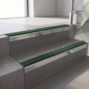 Square-edge aluminium stair nosing with a deep 56mm riser face in Mirroflect Silver, fitted along two vinyl-covered concrete steps in an office stairwell, with a Dark Green anti-slip PVC insert running the full width of each step
