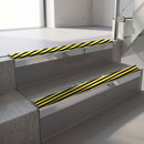 Square-edge aluminium stair nosing with a deep 56mm riser face in Mirroflect Silver, fitted along two vinyl-covered concrete steps in an office stairwell, with a Hazard anti-slip PVC insert running the full width of each step