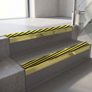 Square-edge aluminium stair nosing with a deep 56mm riser face in Mirrorflect Gold, fitted along two vinyl-covered concrete steps in an office stairwell, with a Hazard anti-slip PVC insert running the full width of each step