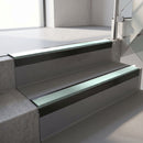 Square-edge aluminium stair nosing with a deep 56mm riser face in Satin Black, fitted along two vinyl-covered concrete steps in an office stairwell, with a Sage Green anti-slip PVC insert running the full width of each step