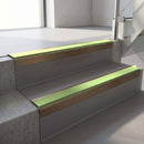 Square-edge aluminium stair nosing with a deep 56mm riser face in Satin Bronze, fitted along two vinyl-covered concrete steps in an office stairwell, with an Apple Green anti-slip PVC insert running the full width of each step