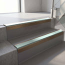 Square-edge aluminium stair nosing with a deep 56mm riser face in Satin Bronze, fitted along two vinyl-covered concrete steps in an office stairwell, with a Sage Green anti-slip PVC insert running the full width of each step