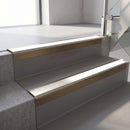 Square-edge aluminium stair nosing with a deep 56mm riser face in Satin Bronze, fitted along two vinyl-covered concrete steps in an office stairwell, with a White anti-slip PVC insert running the full width of each step