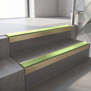 Square-edge aluminium stair nosing with a deep 56mm riser face in Satin Gold, fitted along two vinyl-covered concrete steps in an office stairwell, with an Apple Green anti-slip PVC insert running the full width of each step