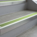 Bright Polished deep-riser square-edge aluminium stair nosing fitted along two bare concrete steps, 62mm tread plate and 56mm front face, with a Apple Green anti-slip insert running the full width of each step