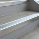 Bright Polished deep-riser square-edge aluminium stair nosing fitted along two bare concrete steps, 62mm tread plate and 56mm front face, with a Aura anti-slip insert running the full width of each step
