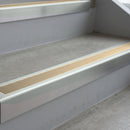 Bright Polished deep-riser square-edge aluminium stair nosing fitted along two bare concrete steps, 62mm tread plate and 56mm front face, with a Beige anti-slip insert running the full width of each step