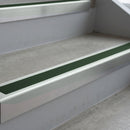 Bright Polished deep-riser square-edge aluminium stair nosing fitted along two bare concrete steps, 62mm tread plate and 56mm front face, with a Dark Green anti-slip insert running the full width of each step