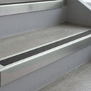 Bright Polished deep-riser square-edge aluminium stair nosing fitted along two bare concrete steps, 62mm tread plate and 56mm front face, with a Dark Grey anti-slip insert running the full width of each step