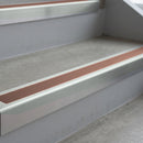 Bright Polished deep-riser square-edge aluminium stair nosing fitted along two bare concrete steps, 62mm tread plate and 56mm front face, with a Mid Brown anti-slip insert running the full width of each step