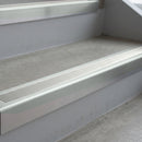 Bright Polished deep-riser square-edge aluminium stair nosing fitted along two bare concrete steps, 62mm tread plate and 56mm front face, with a Oyster anti-slip insert running the full width of each step
