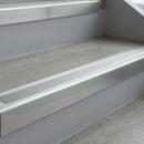 Bright Polished deep-riser square-edge aluminium stair nosing fitted along two bare concrete steps, 62mm tread plate and 56mm front face, with a Polar Grey anti-slip insert running the full width of each step