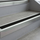 Bright Polished deep-riser square-edge aluminium stair nosing fitted along two bare concrete steps, 62mm tread plate and 56mm front face, with a Premium Black anti-slip insert running the full width of each step