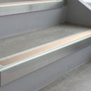 Bright Polished deep-riser square-edge aluminium stair nosing fitted along two bare concrete steps, 62mm tread plate and 56mm front face, with a Sahara anti-slip insert running the full width of each step