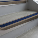 Dark Bronze deep-riser square-edge aluminium stair nosing fitted along two bare concrete steps, 62mm tread plate and 56mm front face, with a Dark Blue anti-slip insert running the full width of each step