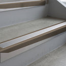 Dark Bronze deep-riser square-edge aluminium stair nosing fitted along two bare concrete steps, 62mm tread plate and 56mm front face, with a Polar Grey anti-slip insert running the full width of each step