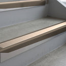 Dark Bronze deep-riser square-edge aluminium stair nosing fitted along two bare concrete steps, 62mm tread plate and 56mm front face, with a Sahara anti-slip insert running the full width of each step
