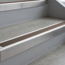 Mill Finish deep-riser square-edge aluminium stair nosing fitted along two bare concrete steps, 62mm tread plate and 56mm front face, with a Brown anti-slip insert running the full width of each step