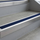 Mill Finish deep-riser square-edge aluminium stair nosing fitted along two bare concrete steps, 62mm tread plate and 56mm front face, with a Dark Blue anti-slip insert running the full width of each step