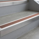 Mill Finish deep-riser square-edge aluminium stair nosing fitted along two bare concrete steps, 62mm tread plate and 56mm front face, with a Mid Brown anti-slip insert running the full width of each step