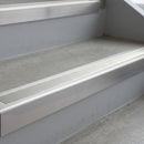 Mill Finish deep-riser square-edge aluminium stair nosing fitted along two bare concrete steps, 62mm tread plate and 56mm front face, with a Oyster anti-slip insert running the full width of each step