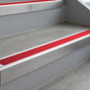 Mill Finish deep-riser square-edge aluminium stair nosing fitted along two bare concrete steps, 62mm tread plate and 56mm front face, with a Red anti-slip insert running the full width of each step