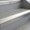 Mill Finish deep-riser square-edge aluminium stair nosing fitted along two bare concrete steps, 62mm tread plate and 56mm front face, with a White anti-slip insert running the full width of each step