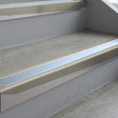 Mirroflect Silver deep-riser square-edge aluminium stair nosing fitted along two bare concrete steps, 62mm tread plate and 56mm front face, with a Aura anti-slip insert running the full width of each step