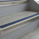 Mirroflect Silver deep-riser square-edge aluminium stair nosing fitted along two bare concrete steps, 62mm tread plate and 56mm front face, with a Blue anti-slip insert running the full width of each step