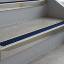 Mirroflect Silver deep-riser square-edge aluminium stair nosing fitted along two bare concrete steps, 62mm tread plate and 56mm front face, with a Dark Blue anti-slip insert running the full width of each step