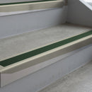 Mirroflect Silver deep-riser square-edge aluminium stair nosing fitted along two bare concrete steps, 62mm tread plate and 56mm front face, with a Dark Green anti-slip insert running the full width of each step